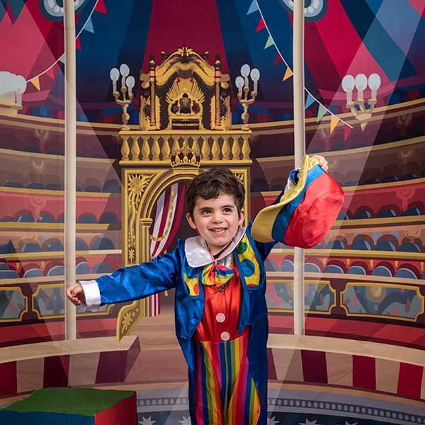 Un niño disfrazado posa sobre un decorado de carnaval