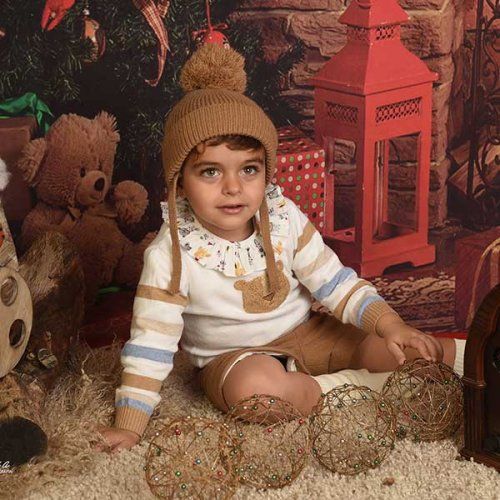 Un niño posa con adornos navideños para una sesión de fotos